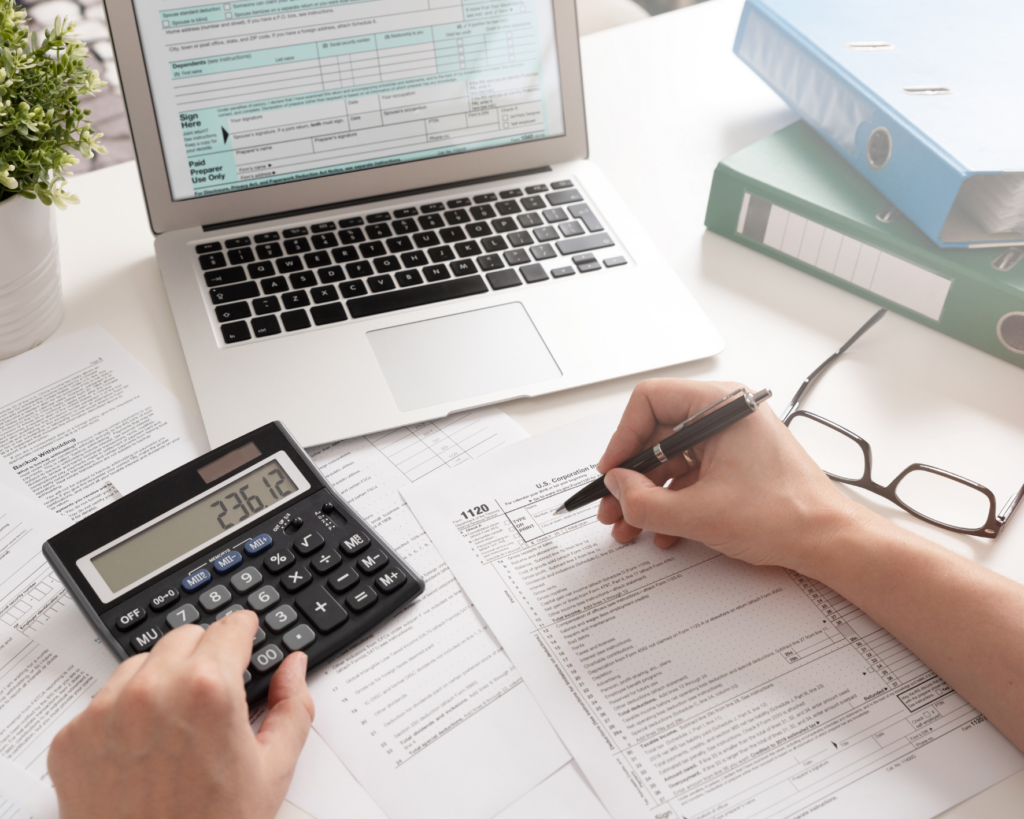Person using a calculator and reviewing tax documents on a laptop while planning Roth IRA contributions and retirement tax strategies.
